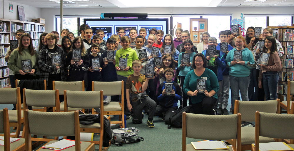 Students and author Keely Hutton take a photo holding copies of "Don't Look Back"